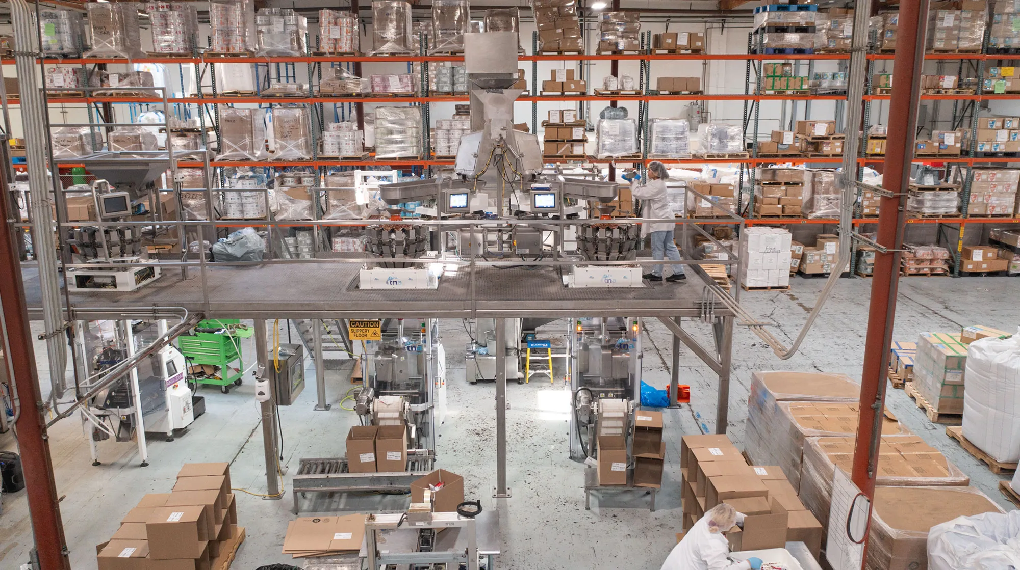 Multihead weighers on a mezzanine above two baggers, with a line worker on the platform