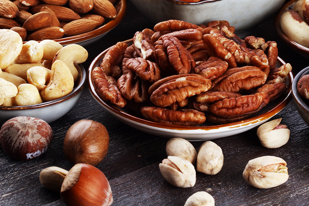 Performance Co-Packing Showing Capabilities You can Count On Bowls of Dried Fruits and Nuts on a Wood Background